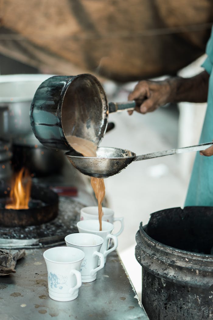 Street vendor prepares and pours traditional chai into cups in Faisalabad, Pakistan.